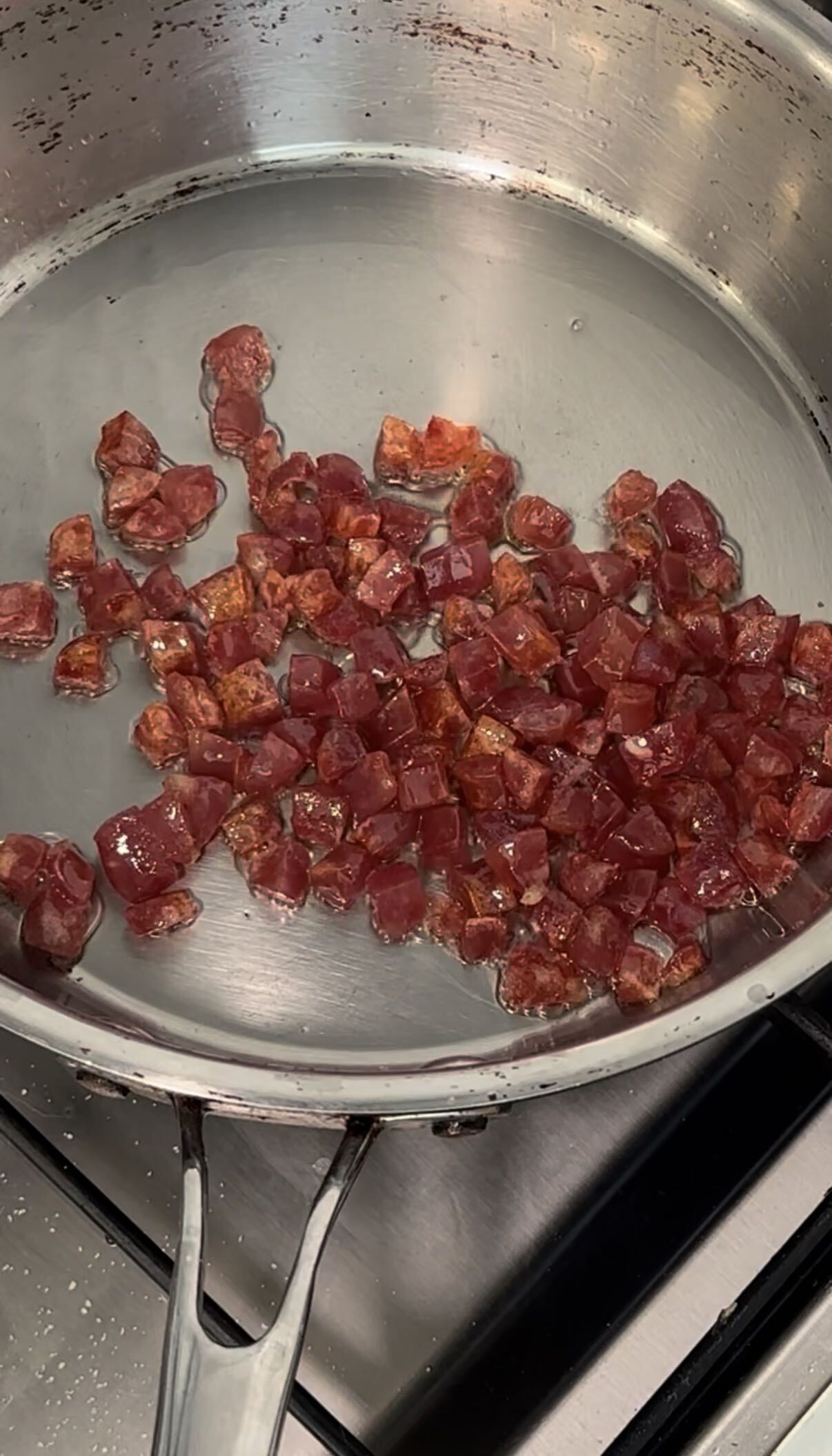 Lap cheong rendering in a pan, edges turning glassy
